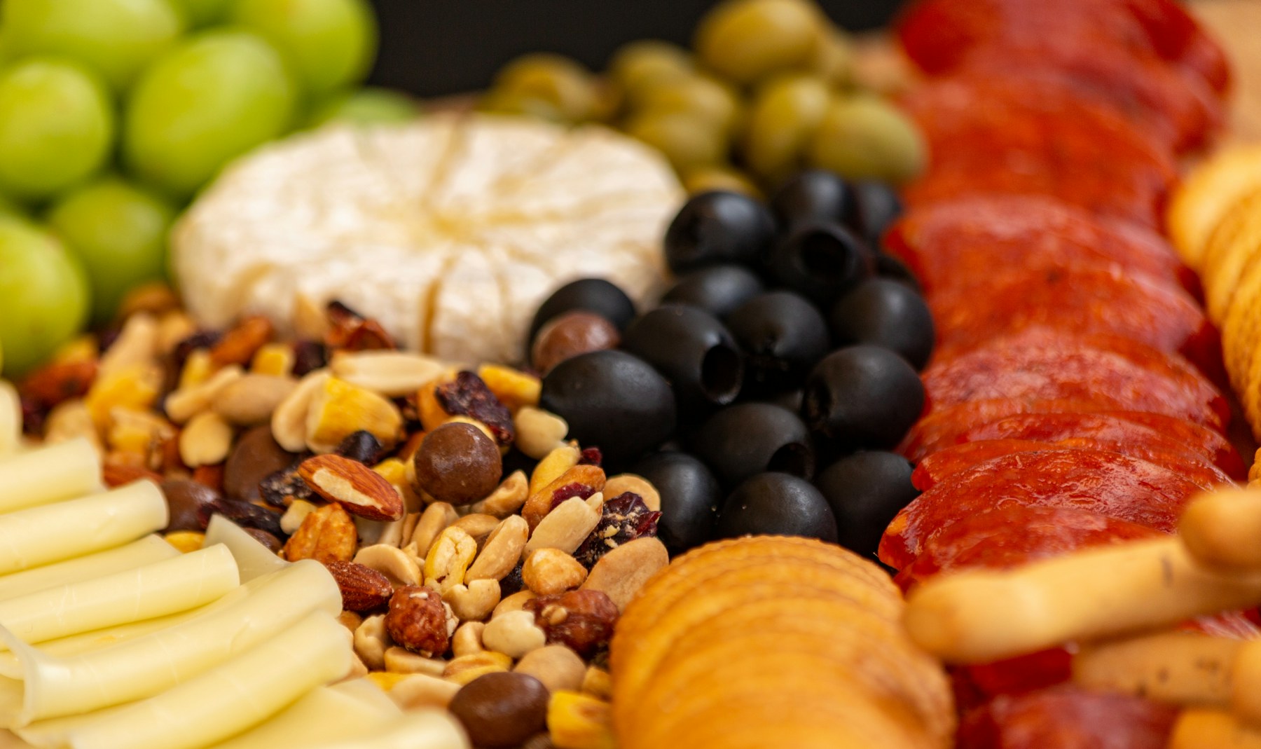 Charcuterie board with cheese, olives, nuts, grapes, crackers, and cured meats